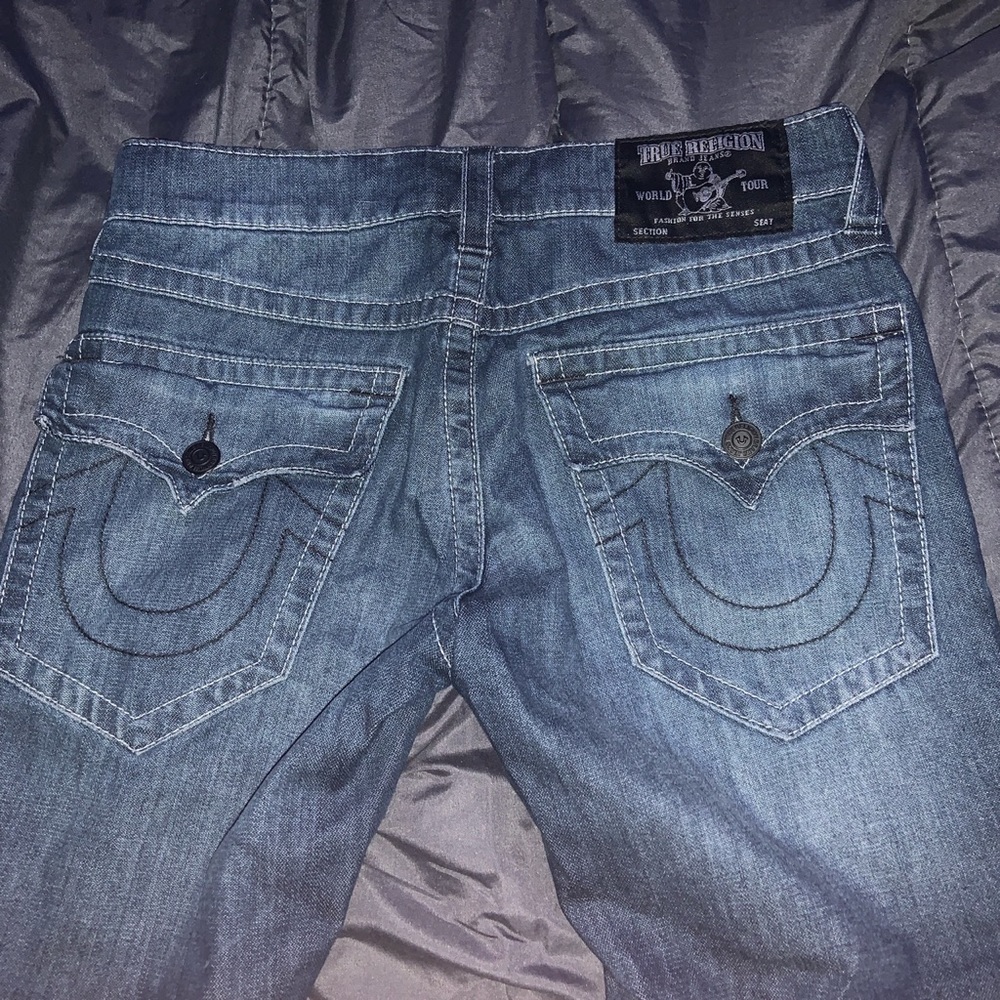 Navy blue True Religion jeans with red flannel patches under holes